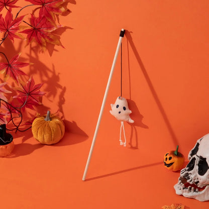 Hanging ghost decoration on a stand with Halloween-themed items on an orange background